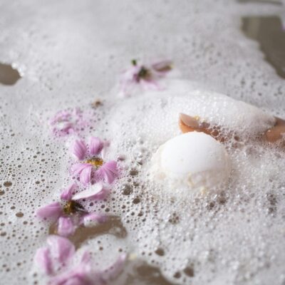 White ball of bath salt on water surface with foam