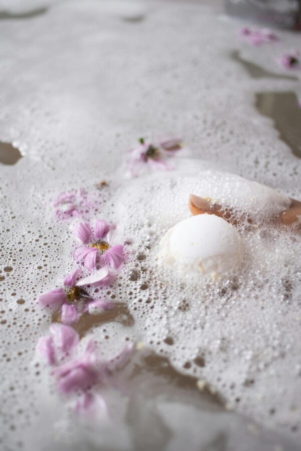 White ball of bath salt on water surface with foam